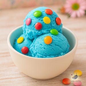 Three scoops of vivid blue coloured ice cream, decorated with colourful milk chocolate buttons in a white bowl on a wooden table